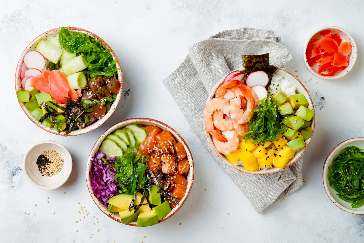 Hawaiianische Lachs-, Thunfisch- und Garnelen-Poke-Bowls mit Algen, Avocado, Mango, eingelegtem Ingwer und Sesam